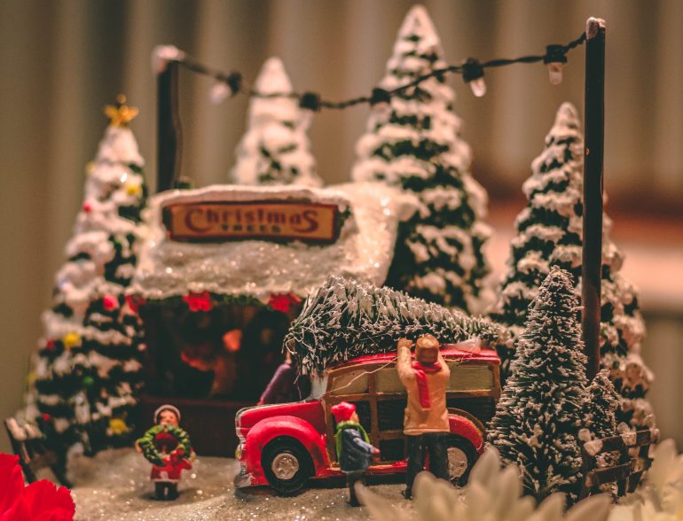 christmas village family attaching tree to red truck