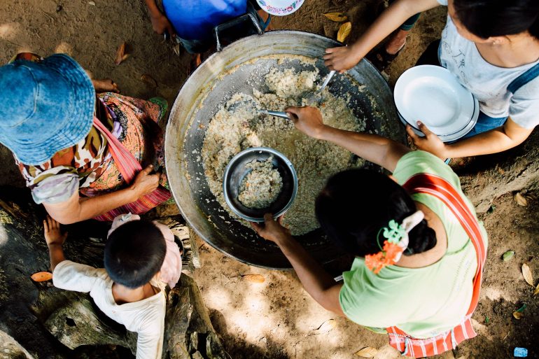 refugees scooping bowls of grits to eat