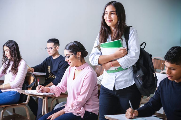 smiling woman standing in classroom filled with students